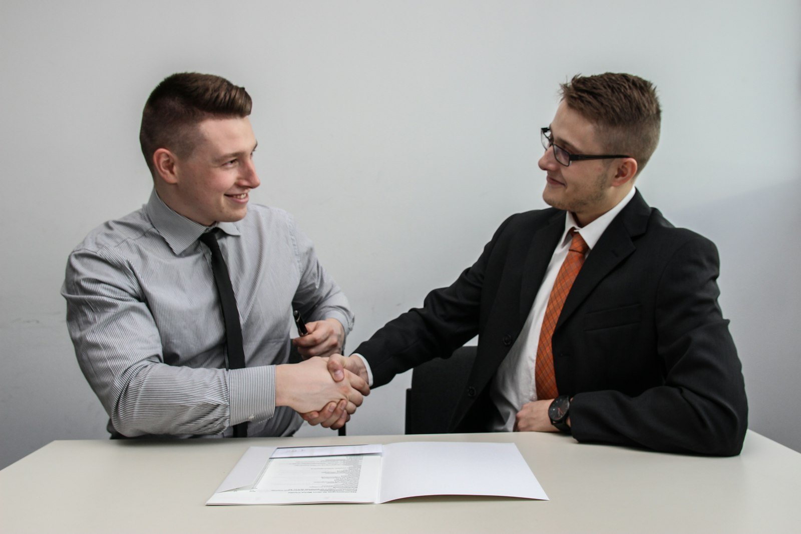 Two professionals shaking hands across a desk